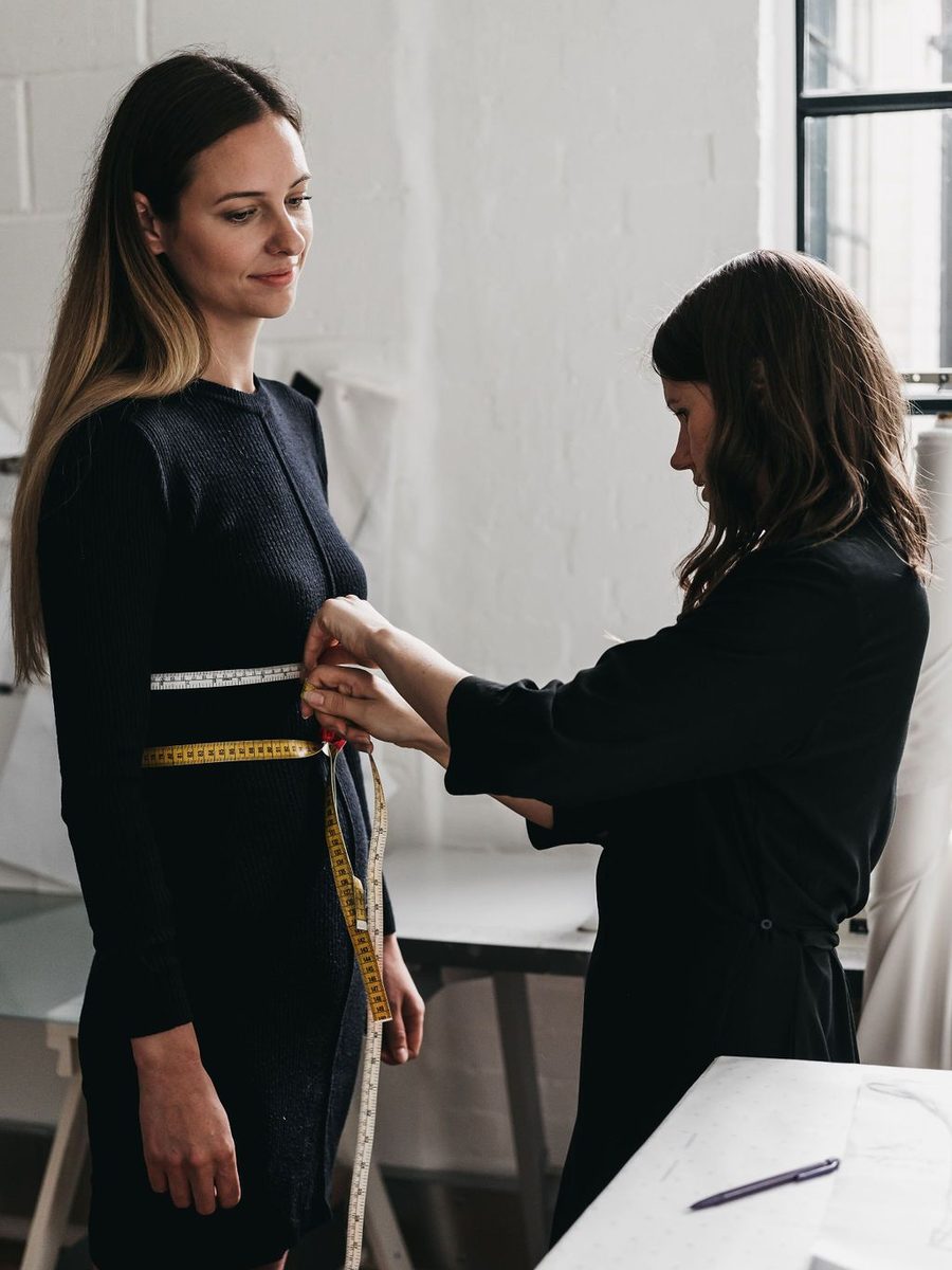 A designer taking a client's measurements with a tape measure