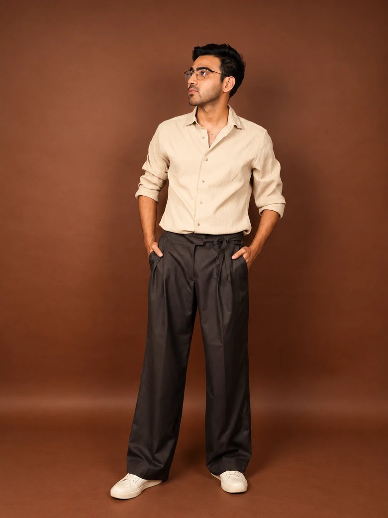 A man in charcoal wide-leg pleated trousers with a tie waist and a beige linen shirt