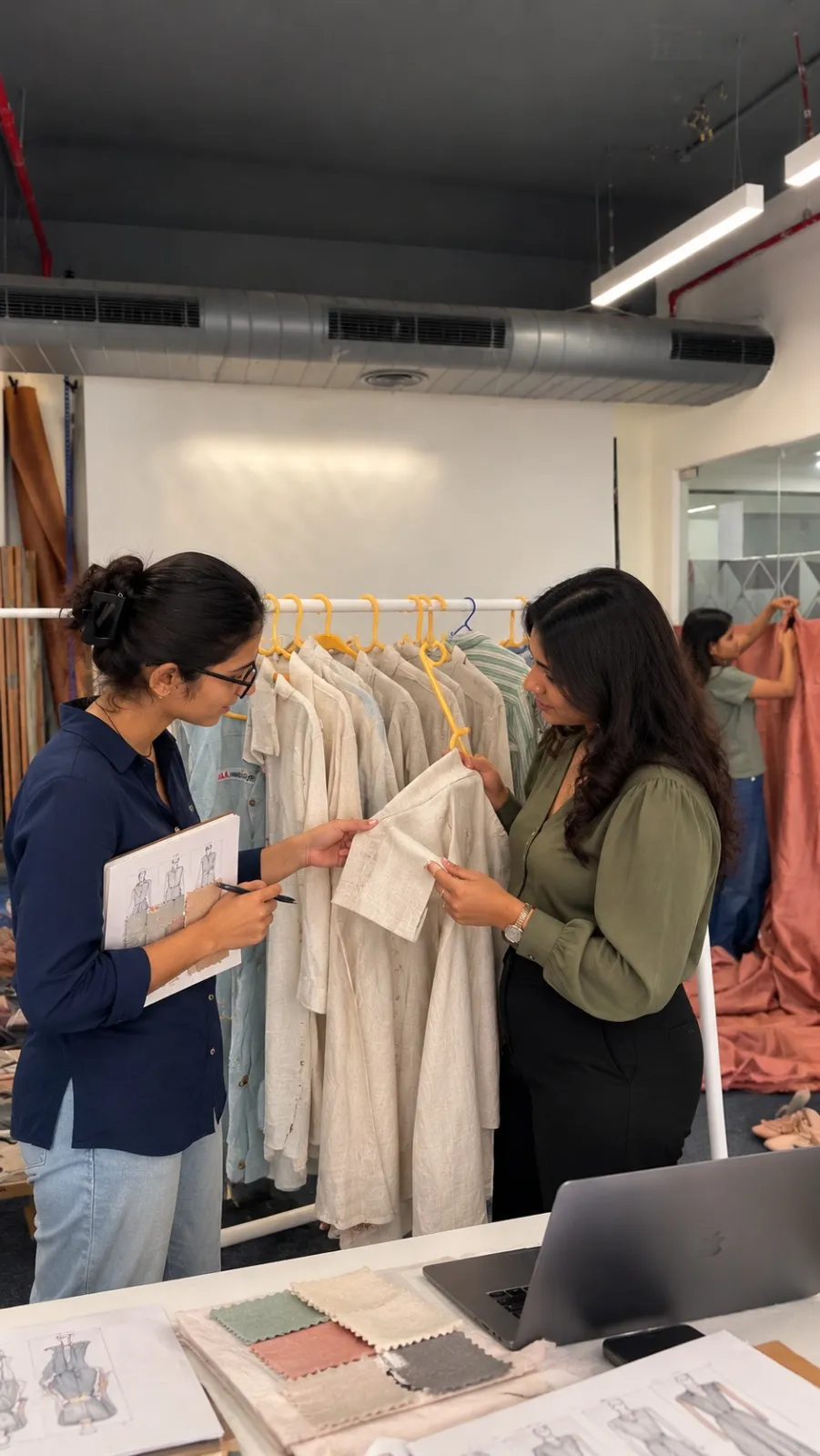 Two founders looking over a garment and fabric swatches together